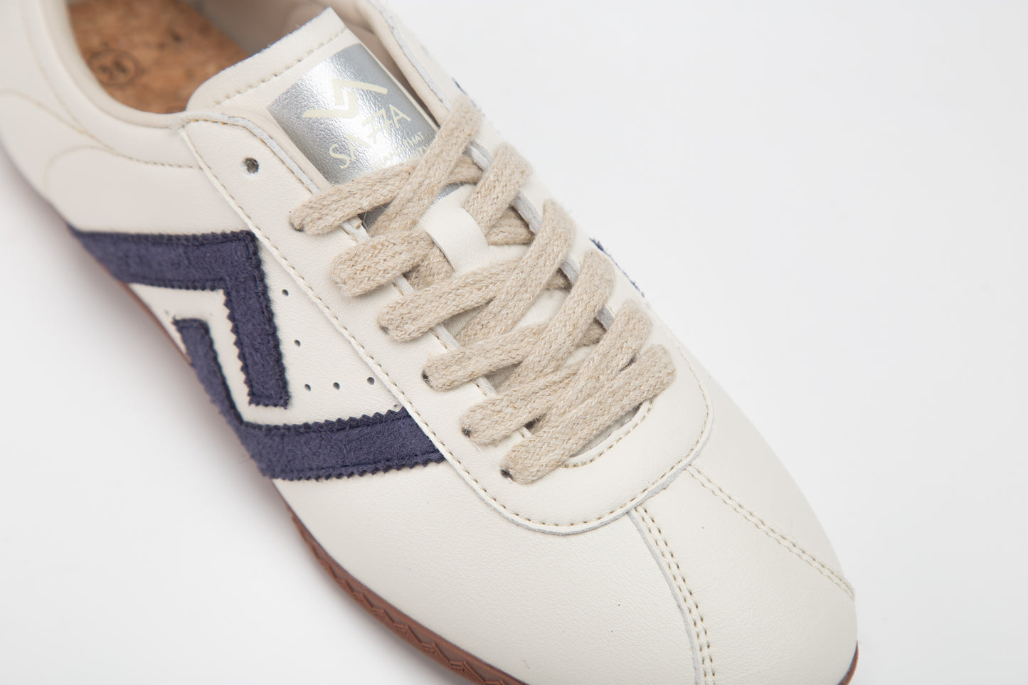 SA77A颯合 AMOY CROWN BLUE. The brand that spells H with double seven. Pair of white sneakers with a blue double seven logo on a light gray background