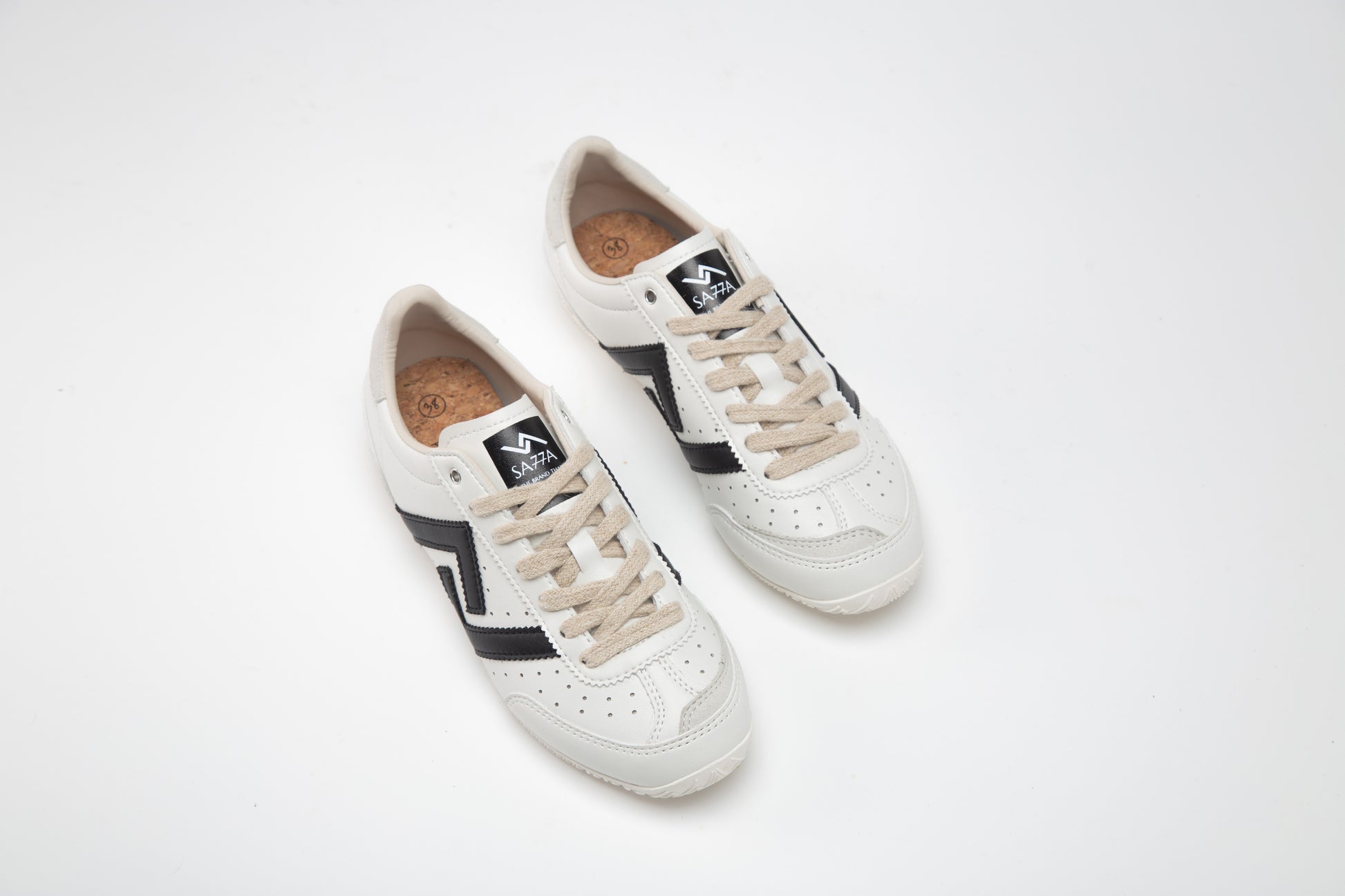 SA77A 颯合Pair of white sneakers with black and beige accents on a light gray background
